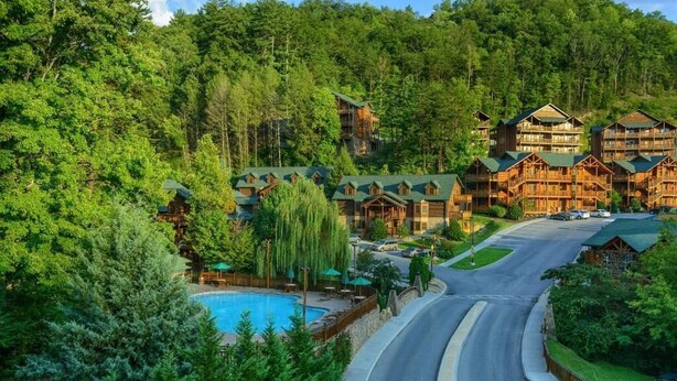 A resort with multiple wooden buildings, a swimming pool, and a curved road.