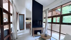 A modern room with a sofa, a small table, a TV, and large windows. - Villa Bohème, Villa 28 (Koh Samui)