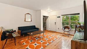 A living room with a blue sofa, a coffee table, a patterned rug, and a television on a wooden stand.