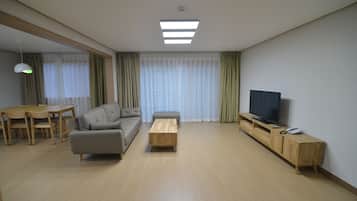 A modern living room with a sofa, coffee table, TV stand, and dining area.