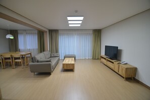 A modern living room with a sofa, coffee table, TV stand, and dining area. - Muju Deogyusan Resort (Muju)