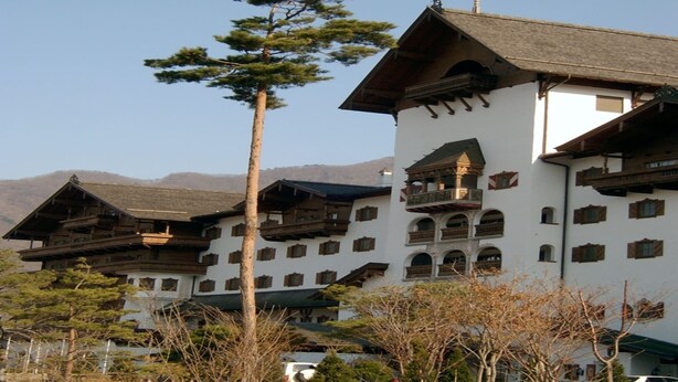 A traditional multi-story building with wooden balconies and a steeply pitched roof, surrounded by trees and mountains in the background. - Muju Deogyusan Resort (Muju)