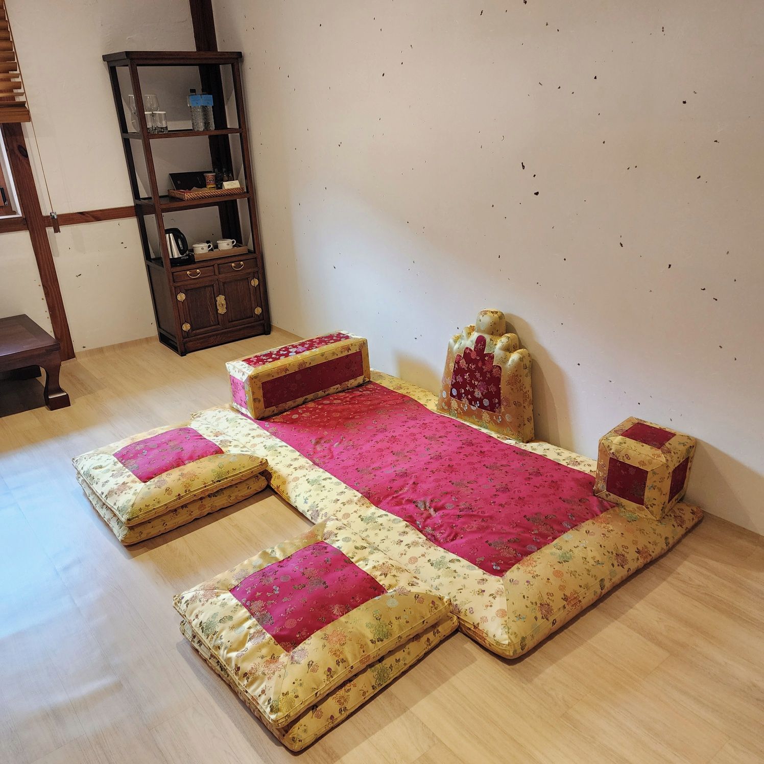 A room with a bed, a wooden cabinet, and a small table.