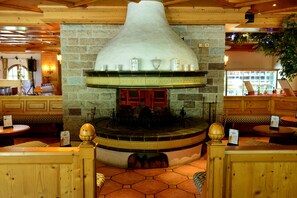 A stone fireplace with a decorative hood, surrounded by wooden seating and tables. - Muju Deogyusan Resort (Muju)