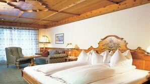 A hotel room with a large bed, two chairs, a small table, a lamp, and a wooden headboard with a floral design. - Muju Deogyusan Resort (Muju)