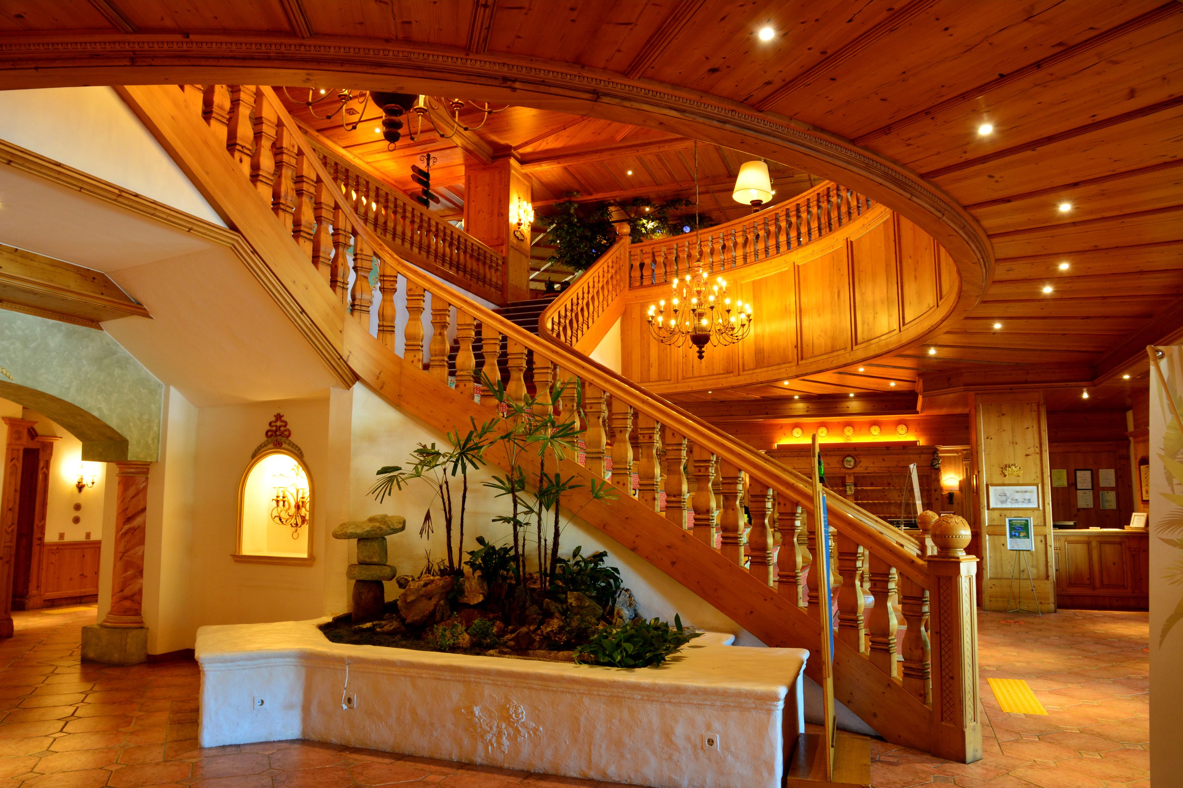 A grand staircase with a curved design, wooden railings, and a chandelier.