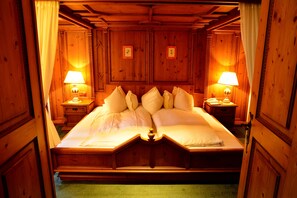 A wooden four-poster bed with white linens and pillows, flanked by two bedside tables with lamps, in a room with wooden paneling and a green carpet. - Muju Deogyusan Resort (Muju)