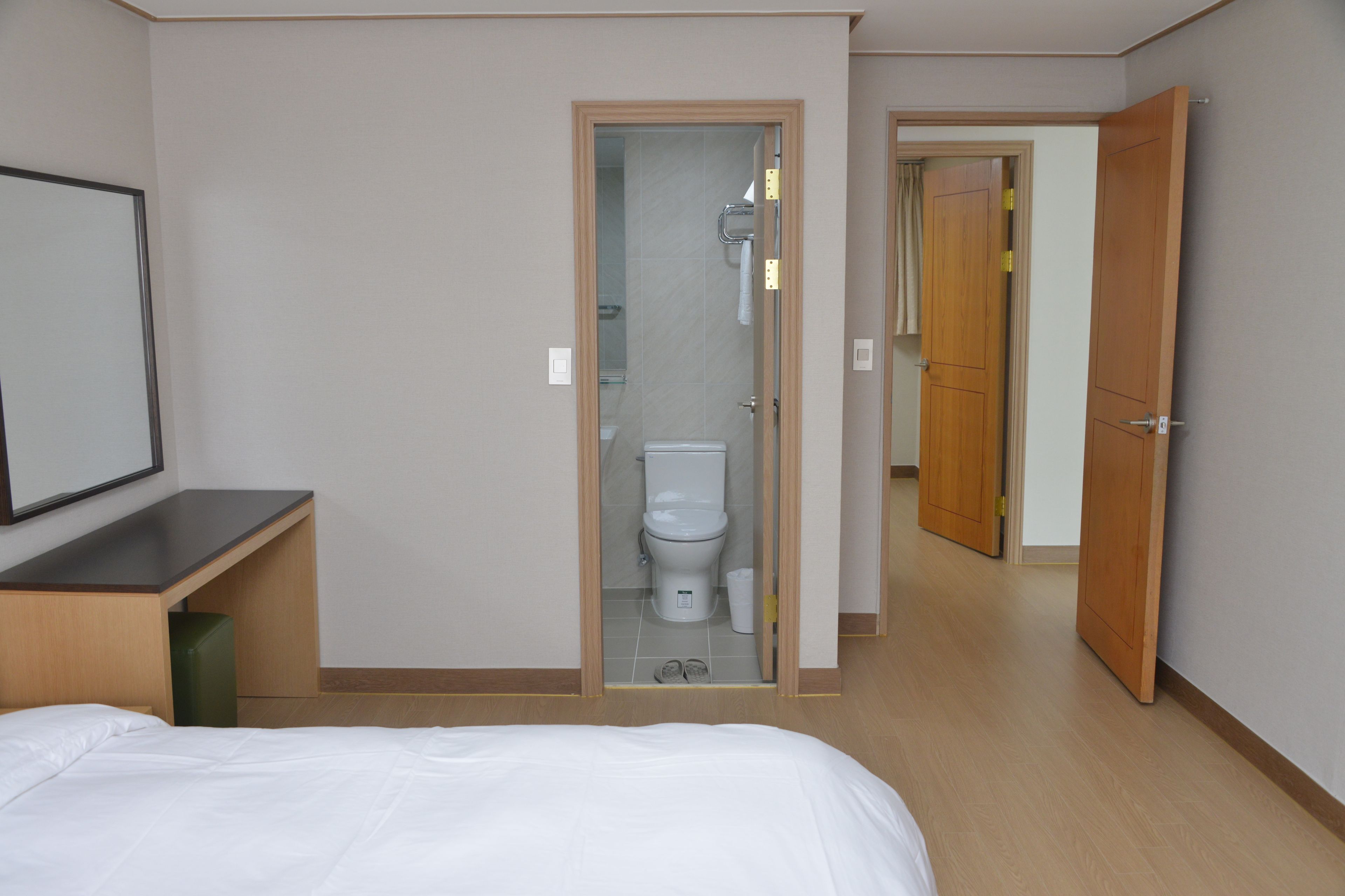 A hotel room with a bed, a bathroom with a toilet, and a shower.