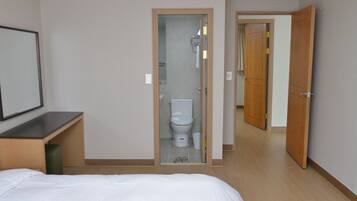 A hotel room with a bed, a bathroom with a toilet, and a shower.
