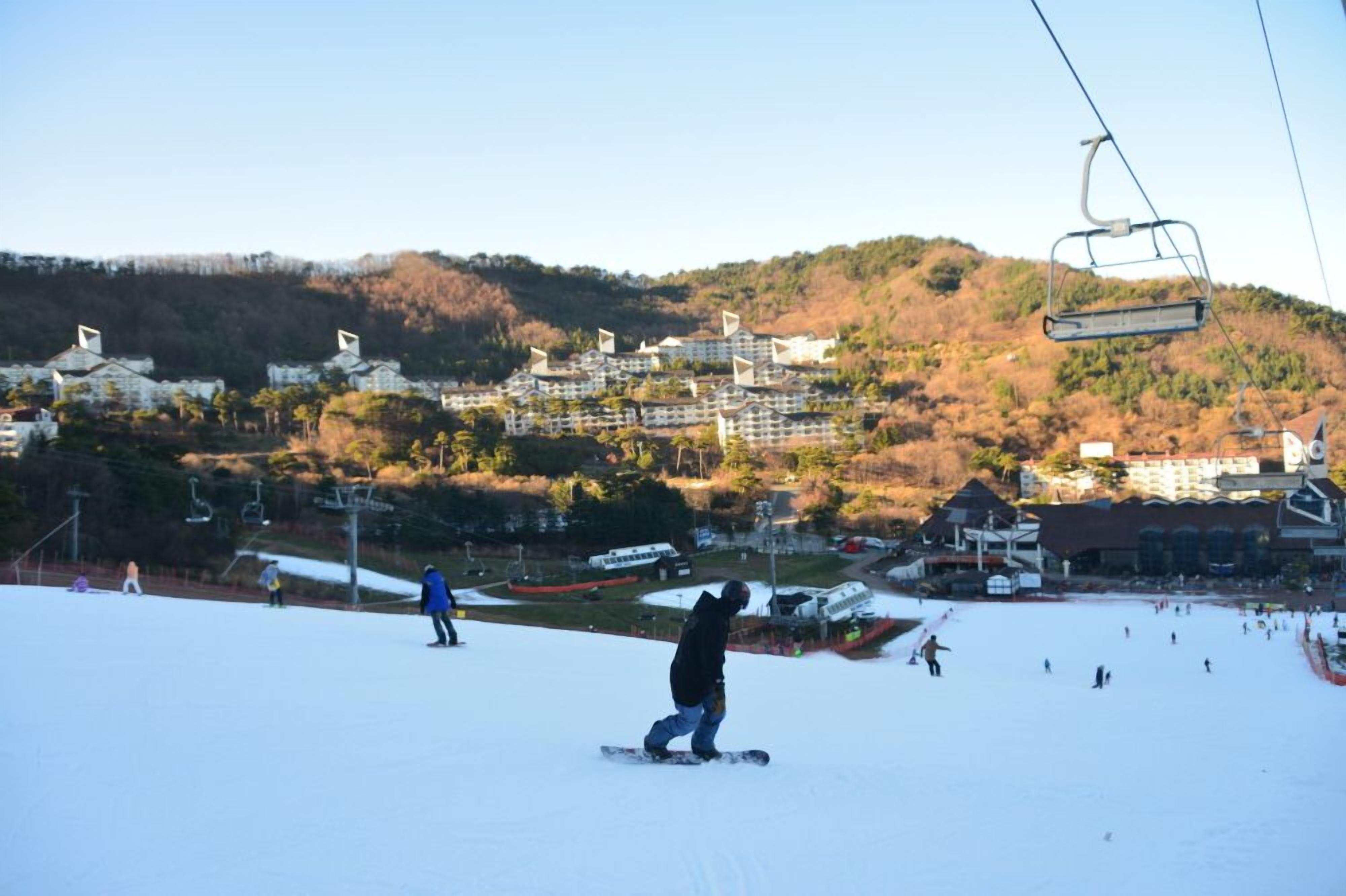 A ski resort with a chairlift, snow-covered slopes, and buildings in the background.