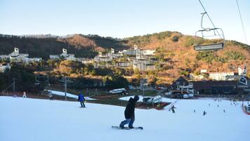 A ski resort with a chairlift, snow-covered slopes, and buildings in the background.