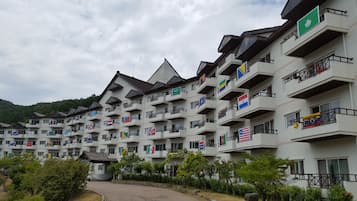 A multi-story hotel with balconies, flags, and a mountainous backdrop.