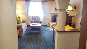 A hotel room with a blue carpet, a wooden table, a sofa, and a lamp.