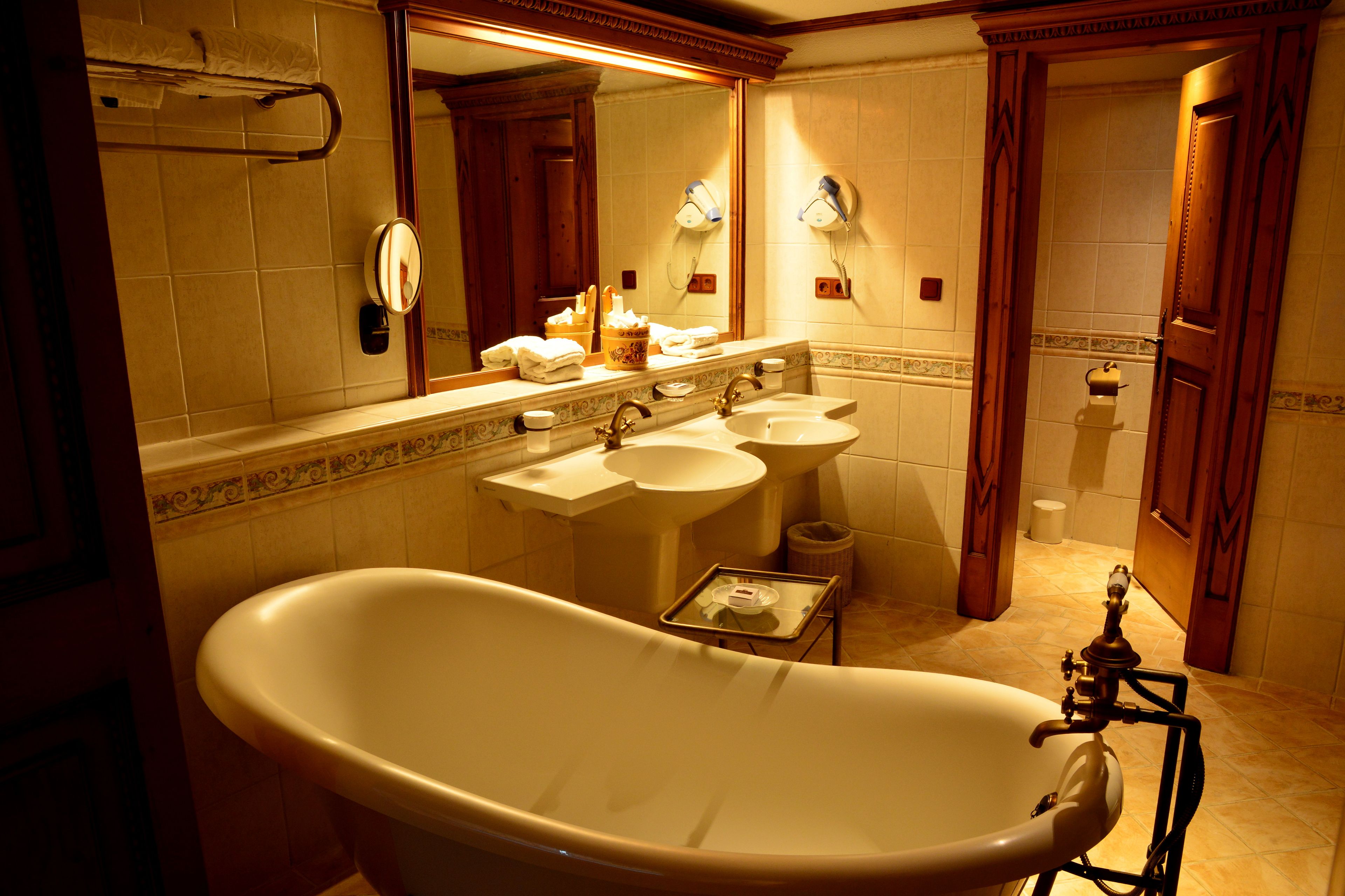 Un baño clásico con una bañera independiente, dos lavamanos y un espejo grande.