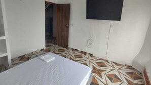 A room with a bed, a TV mounted on the wall, and patterned flooring. - Hospedaje ASL HOME (Yumbo)