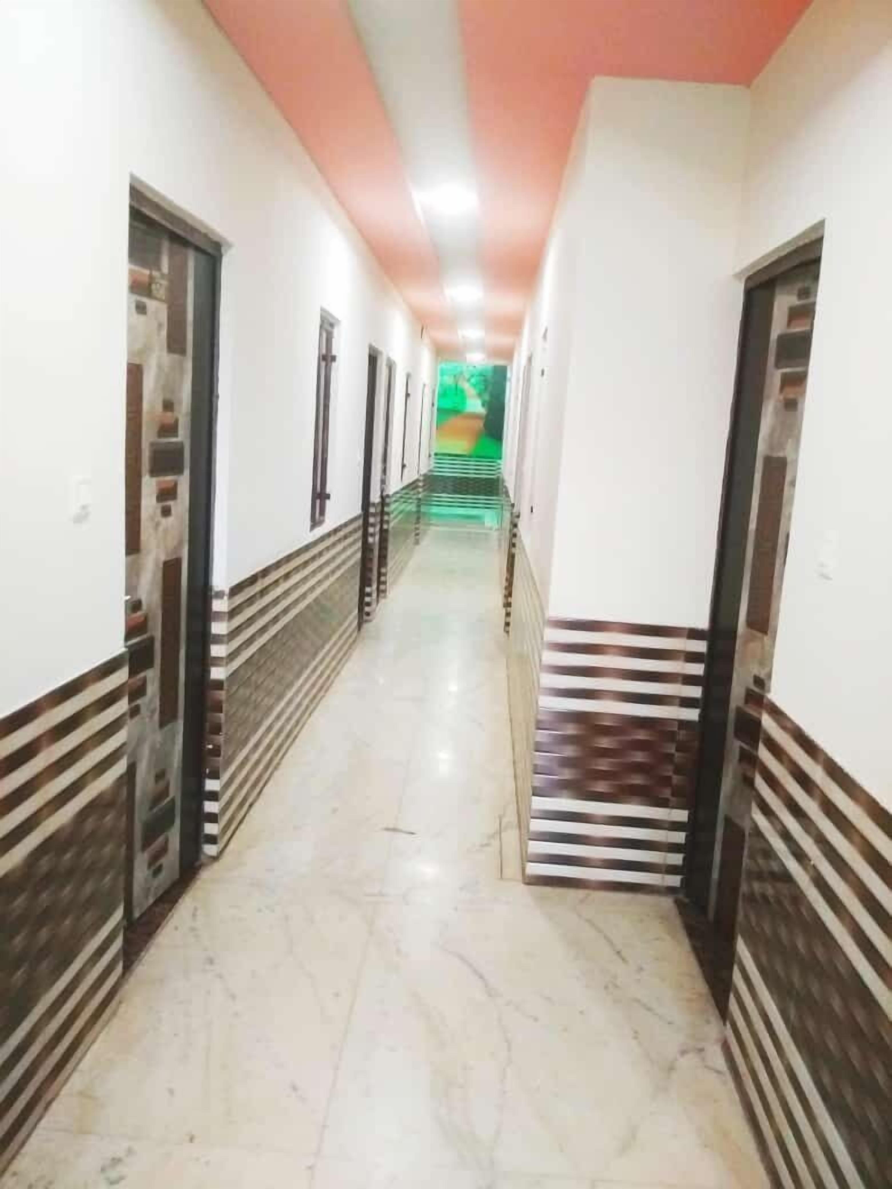 A hallway with white walls, a marble floor, and doors with patterned designs.