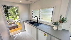 Uma cozinha moderna com fogão a gás, pia e janela com persianas.