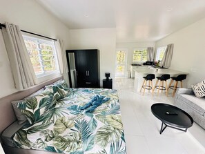 A modern living room with a sofa, a coffee table, and a kitchen area with a dining set.