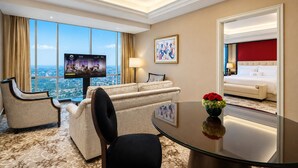 Habitació d'hotel amb una finestra gran, televisió, sofà, taula de dinar i llit.