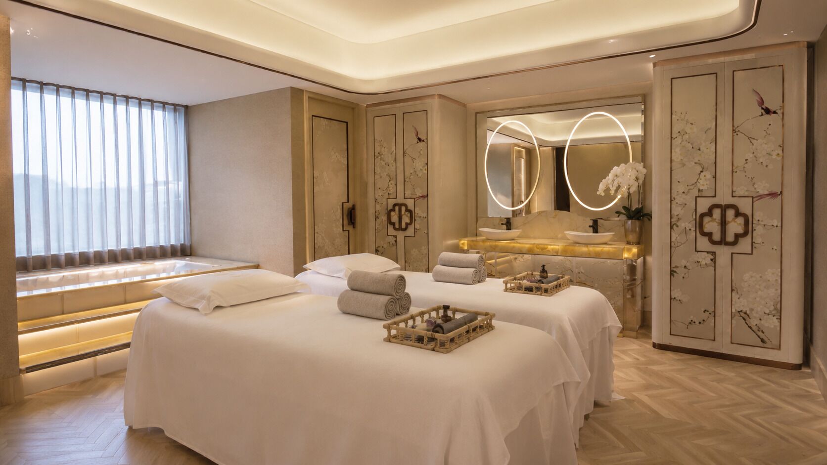 A hotel room with two beds, a bathroom with a large mirror, and a view of the outdoors.