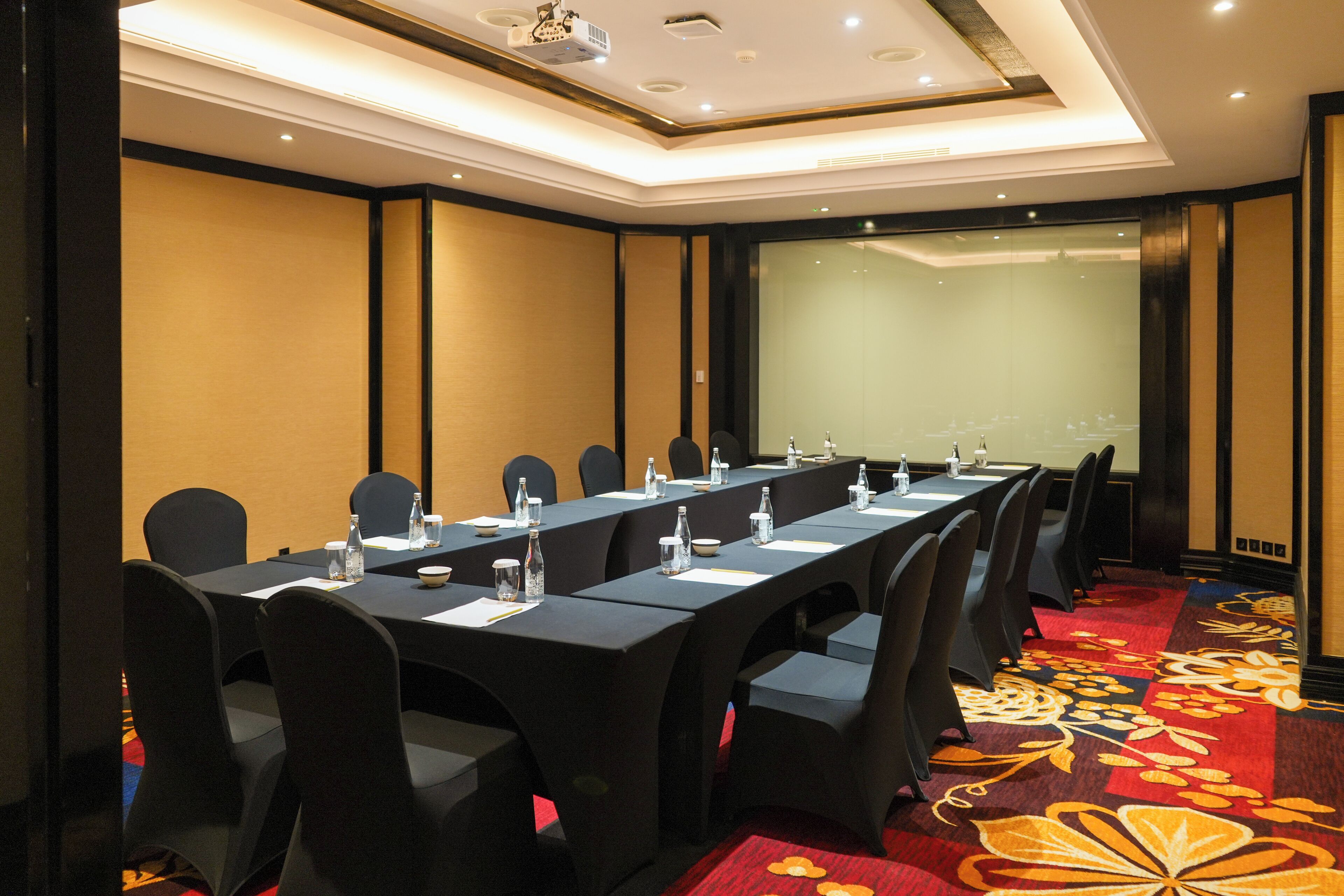 A conference room with a long table, chairs, and a projector screen.