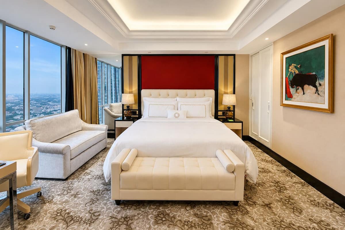 A hotel room with a large bed, a sofa, a desk, and a view of the city.
