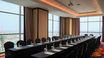 Un salón de conferencias con una larga mesa, sillas y vistas a la ciudad a través de amplias ventanas.