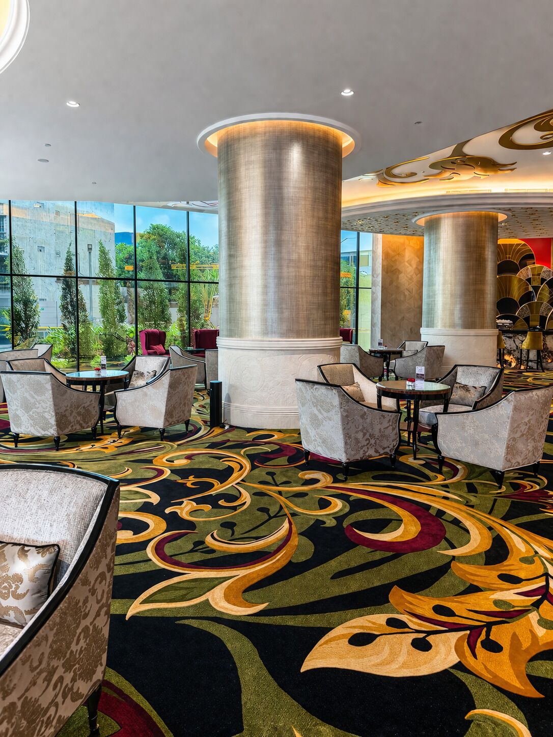 Un hall d’hôtel doté d’une grande fenêtre, d’un espace salon et de colonnes décoratives.