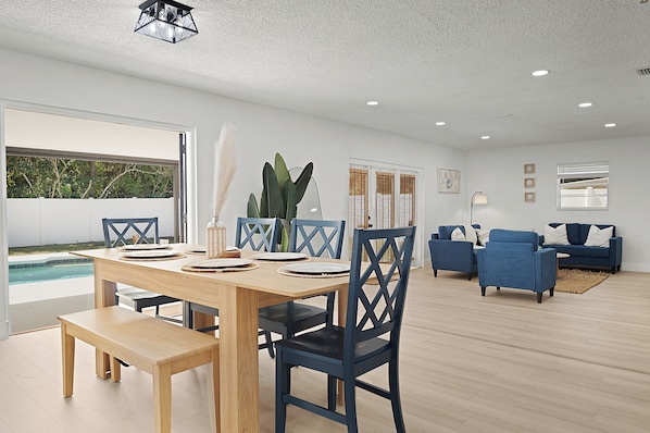 A spacious living area with a dining table, blue chairs, and a blue sofa.