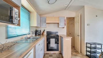 A compact kitchen with a stove, oven, sink, and cabinets.