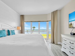 Une chambre d’hôtel avec un grand lit, une télévision et vue sur la plage.