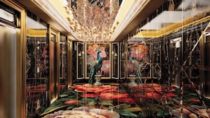 Ein luxuriöser Flur mit einer Pfauenstatue, einem floralen Bodenmuster und einem Chandelier.