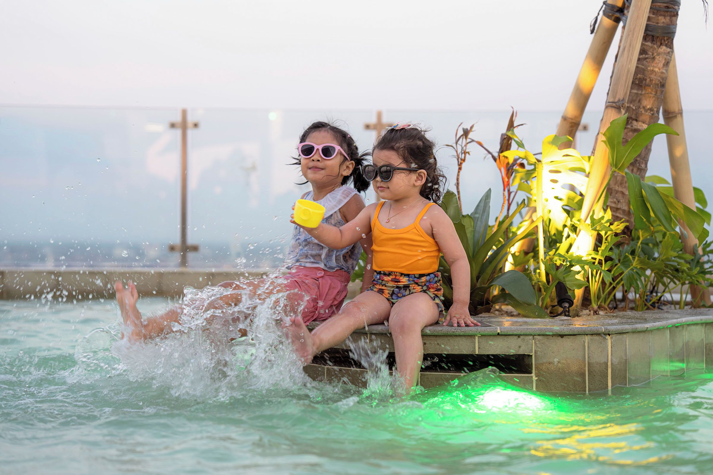 Two children playing in a pool with water splashing around them.