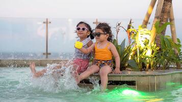 Two children playing in a pool with water splashing around them.