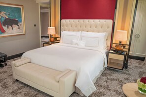 A hotel room with a large bed, a bedside table with a lamp, a bench, and a painting on the wall. - The Trans Luxury Hotel Surabaya (Surabaya)