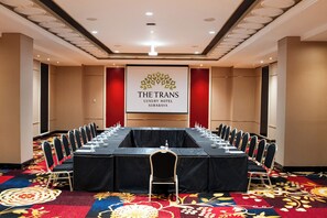 A conference room at The Trans Luxury Hotel in Surabaya with a long table, chairs, and a projector screen. - The Trans Luxury Hotel Surabaya (Surabaya)
