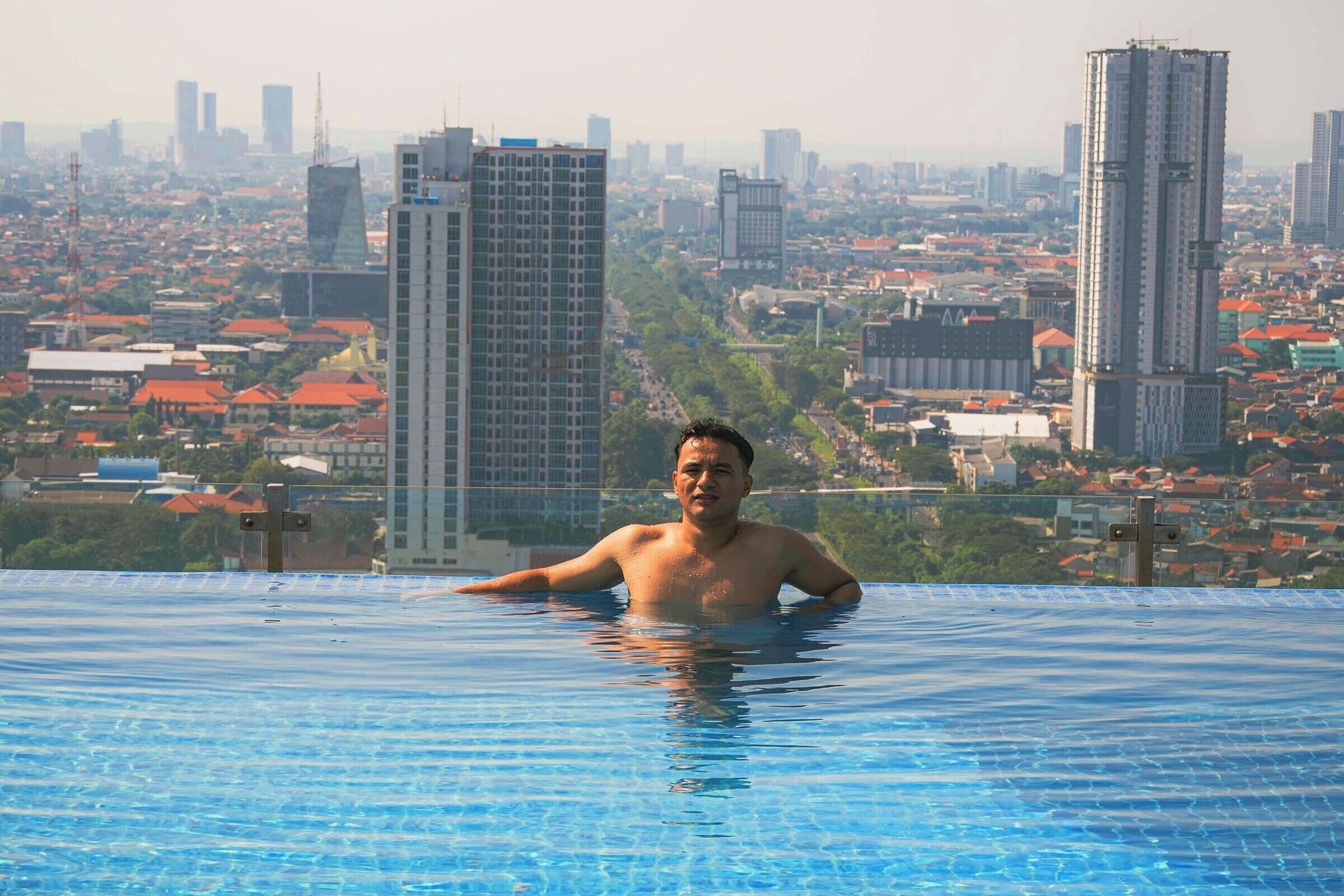 A man in a swimming pool with a cityscape in the background.