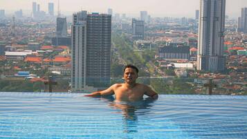 A man in a swimming pool with a cityscape in the background.