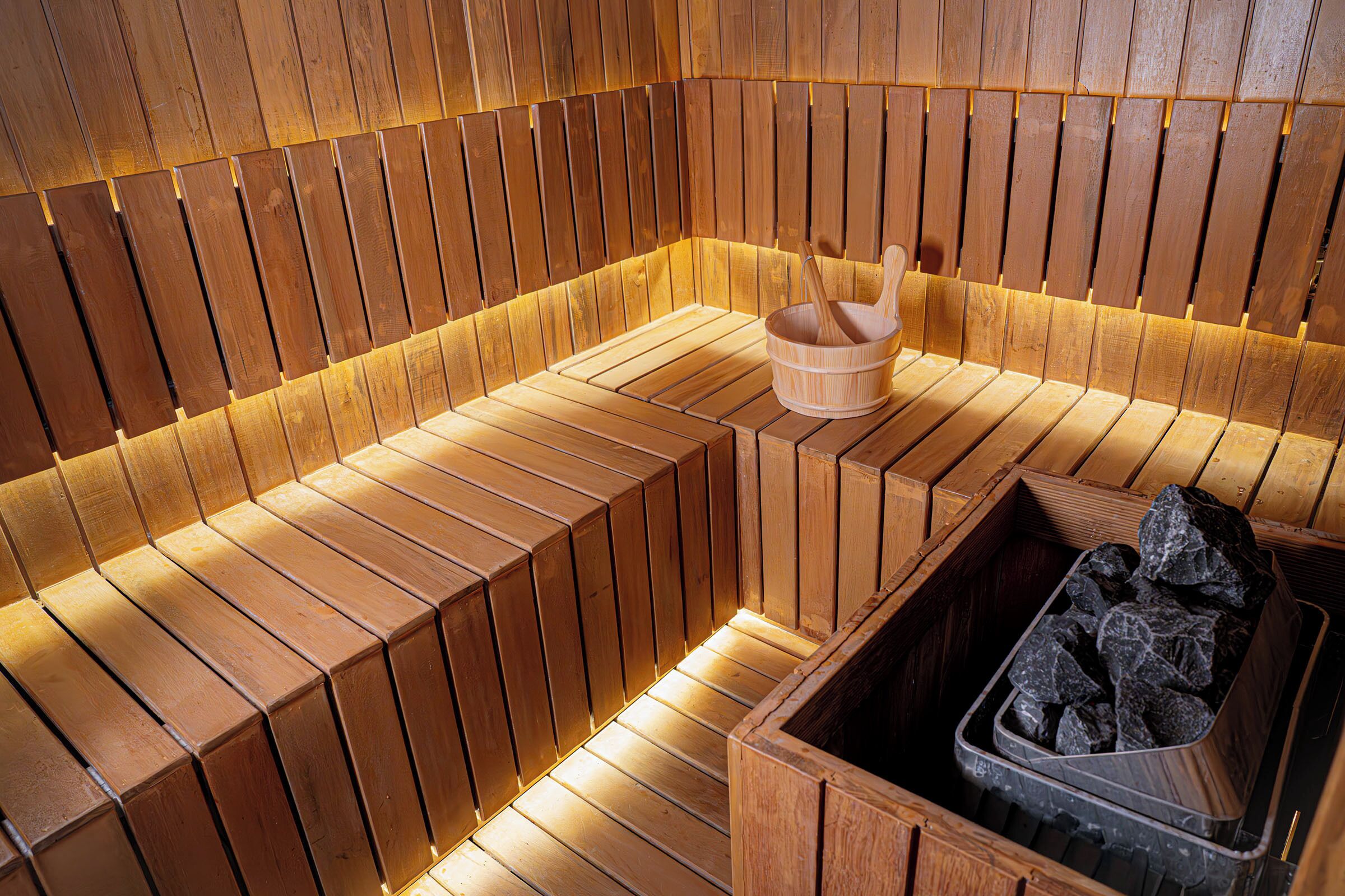 A sauna with wooden benches and a wooden bucket.