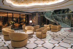 A luxurious lobby with a spiral staircase, wicker furniture, and a patterned floor.