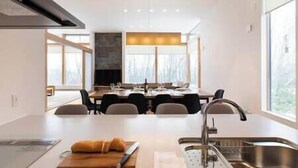 A modern kitchen with a central island, a dining area, and large windows. - Aoyama Lodge | 4BR Chalet in Kabayama | Stunning Mt. Yotei Views (Kutchan-cho)