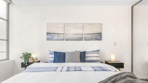 A bedroom with a bed, a nightstand, a lamp, and a wall-mounted artwork. - A Stylish Apt, City Views Next To Darling Harbour (Sydney)