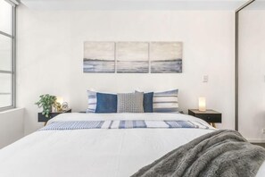 A bedroom with a bed, a nightstand, a lamp, and a wall-mounted artwork. - A Stylish Apt, City Views Next To Darling Harbour (Sydney)
