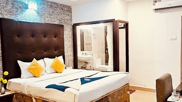 A modern bedroom with a marble headboard, a large bed, a desk, and a chair. - Candolim Sands (Candolim)