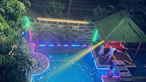 A pool area with a neon-lit edge, surrounded by potted plants and palm trees. - Candolim Sands (Candolim)