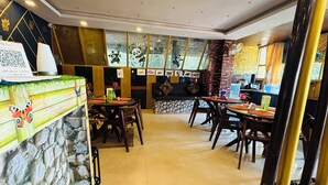 A restaurant interior with a stone wall, wooden furniture, and a mural of pandas. - Candolim Sands (Candolim)