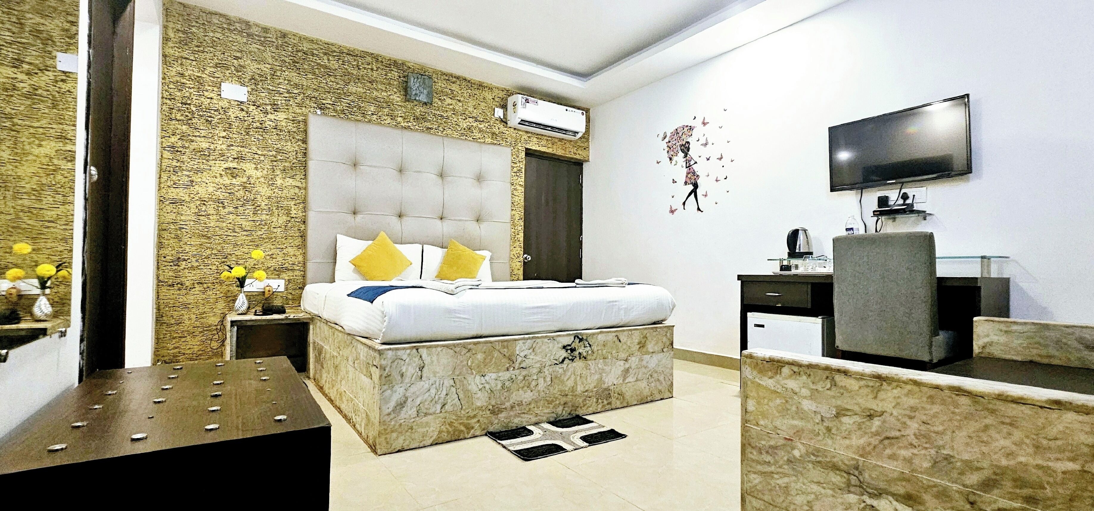 A modern hotel room with a marble bed, a flat-screen TV, a marble vanity, and a stone-textured wall.