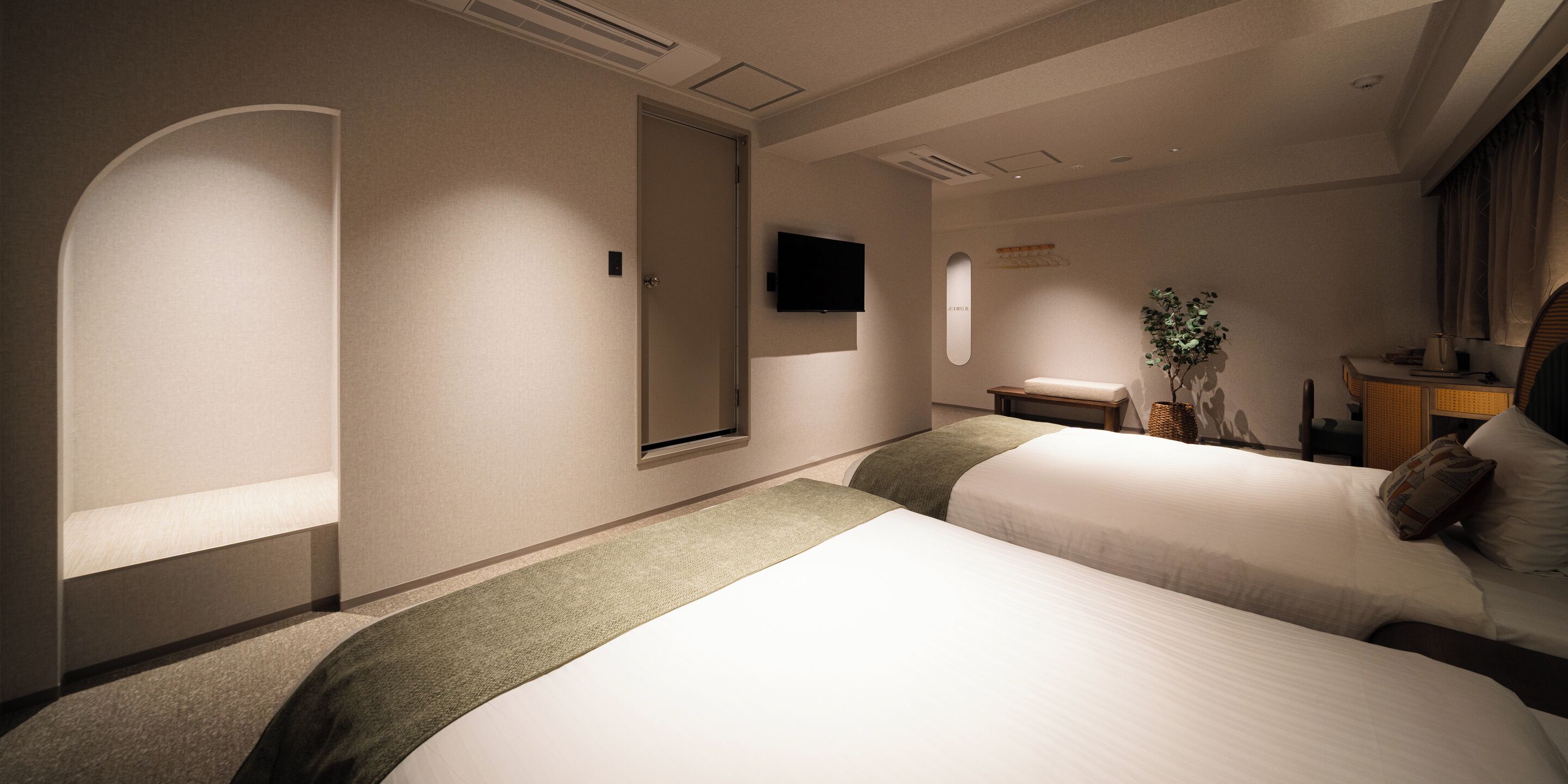 Een hotelkamer met twee bedden, een flatscreen televisie, een klein tafeltje en een plant.