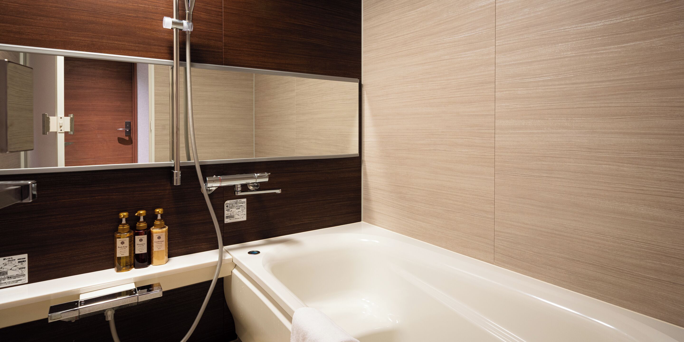 A modern bathroom with a bathtub, a mirror, and a shelf with toiletries.