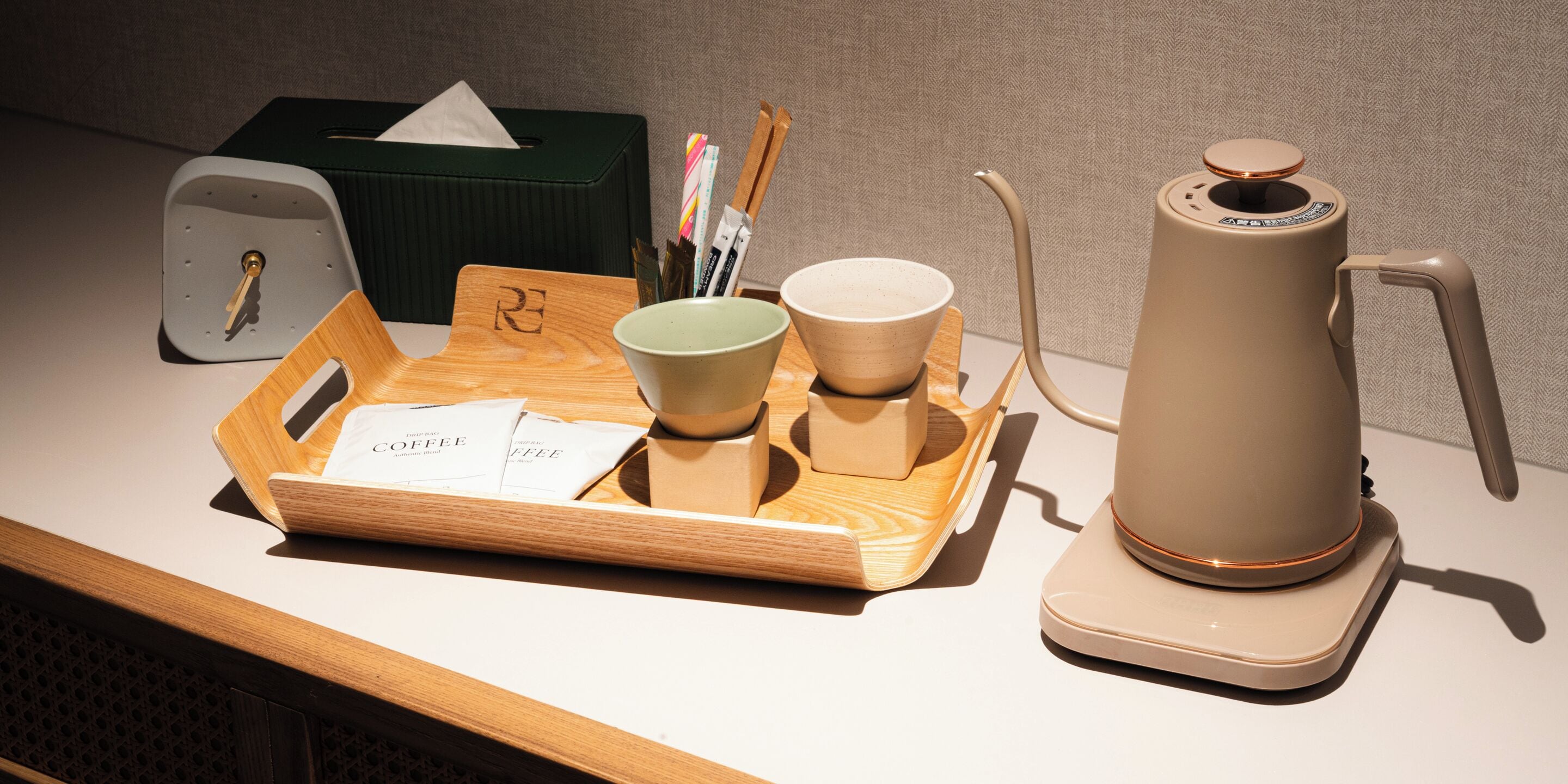A tray with a coffee maker, cups, and a tissue box on a table.